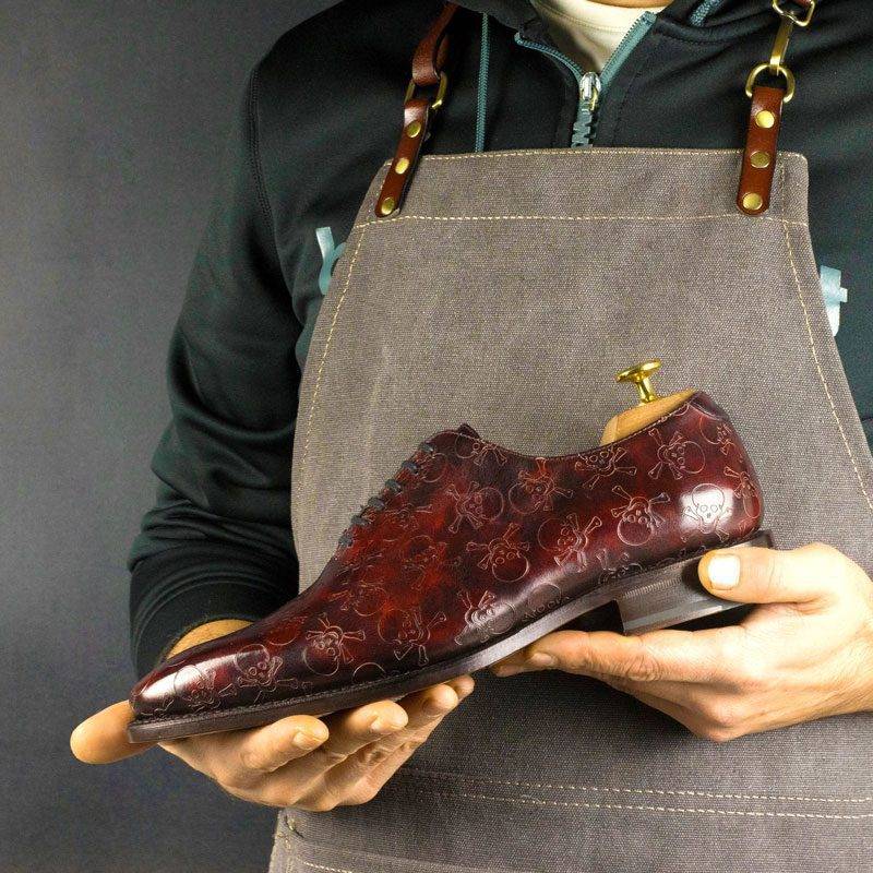 Goodyear welted pair of wholecut shoes, featuring a skull pattern, which is laser engraved on the crust calf leather. The crust is hand painted and finished by our maestro colorist. It features the astonishing burgundy museum patina, which is applied in round motions with brushes and sponges for a unique effect. The pair features a brown leather outsole and brown full-calf inner lining. In terms of construction, they are made using the 872 shoe last: a soft chisel toe and a long elegant vamp.